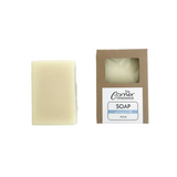 Bar of soap next to its packaging on a white background
