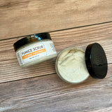Pumice scrub jar with open lid on a wooden surface